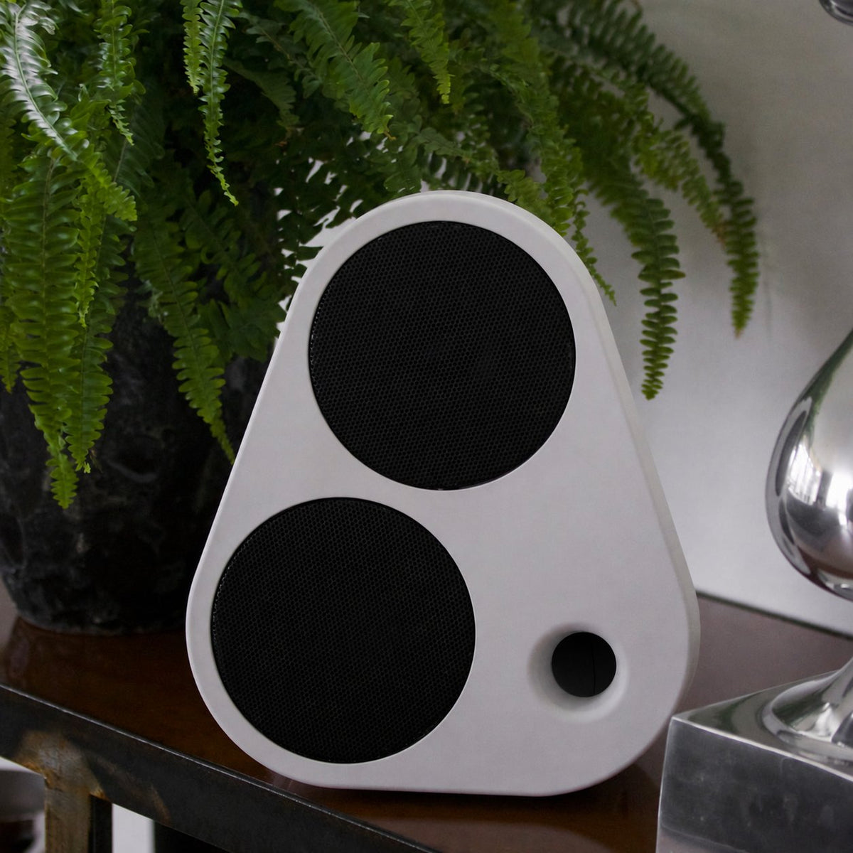 White ES2 on wooden furniture beneath a green plant #color_white